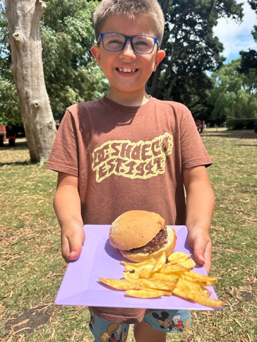 Chico con su almuerzo del buffet de la colonia: hamburguesa con papas fritas